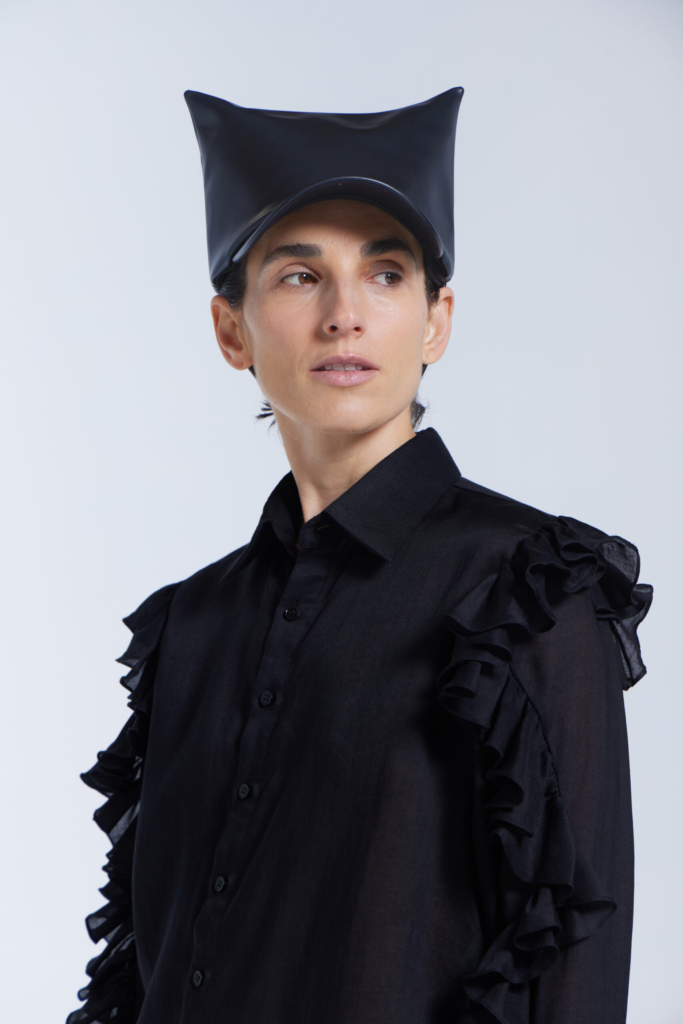 Model wearing KimC Studio sculptural faux leather cap with architectural peaks