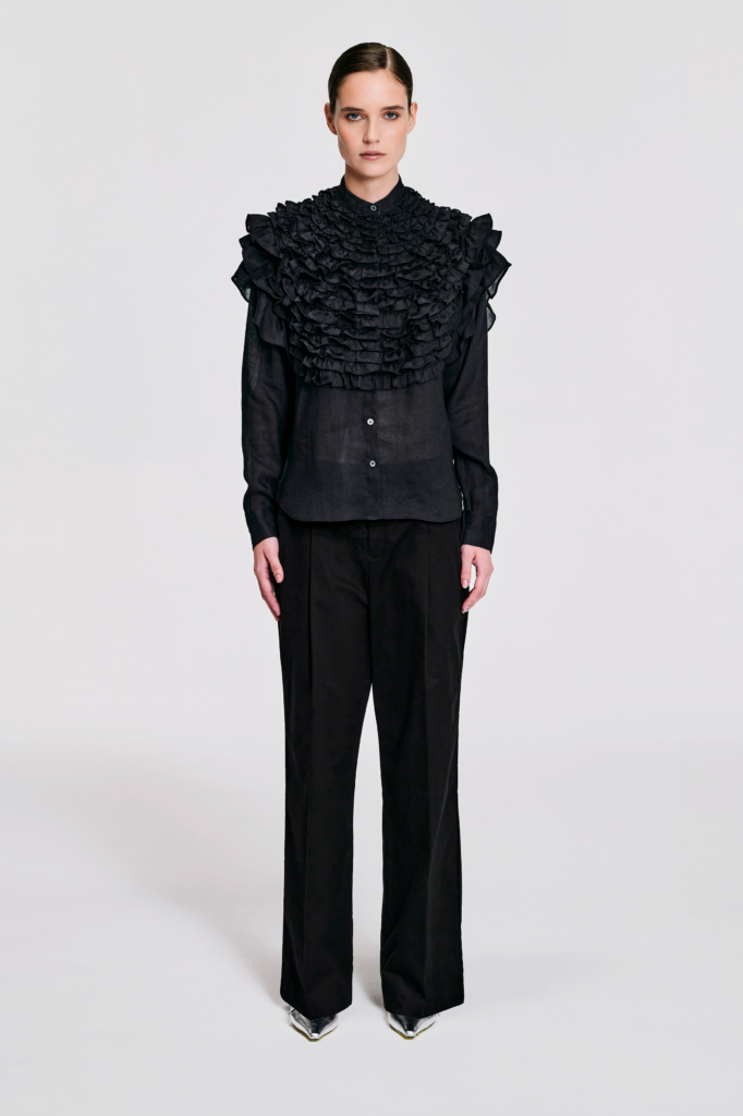 Model wearing a black hemp ruffle sleeve shirt with sculptural shoulder ruffles, pointed collar, button-front closure, and relaxed silhouette by KimC Studio.