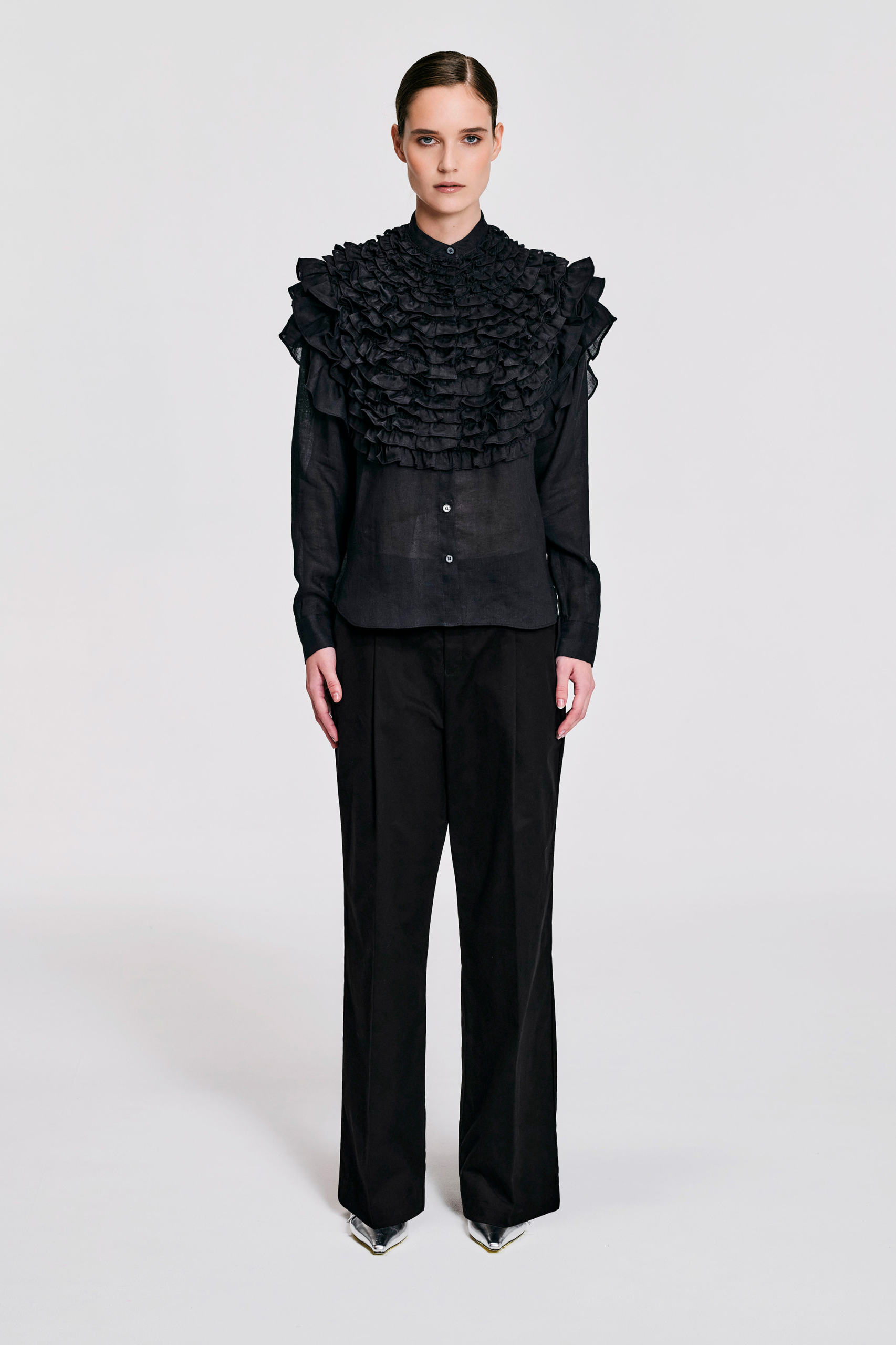 Model wearing a black hemp ruffle sleeve shirt with sculptural shoulder ruffles, pointed collar, button-front closure, and relaxed silhouette by KimC Studio.