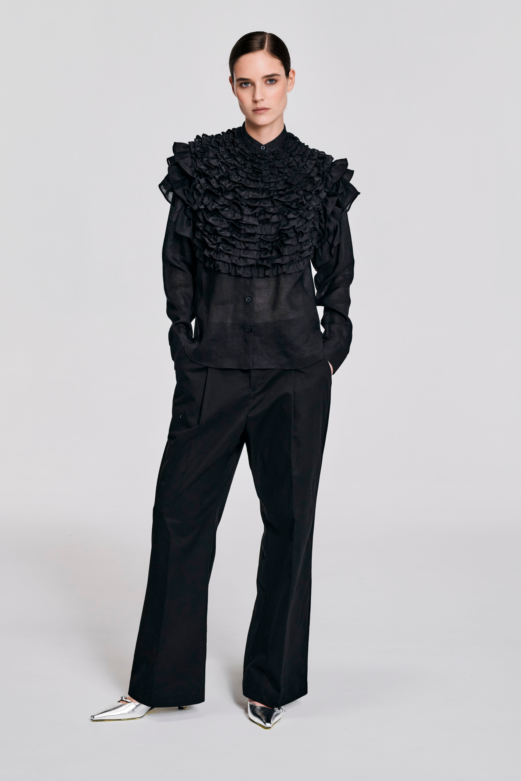 Model wearing a black hemp ruffle sleeve shirt with sculptural shoulder ruffles, pointed collar, button-front closure, and relaxed silhouette by KimC Studio.