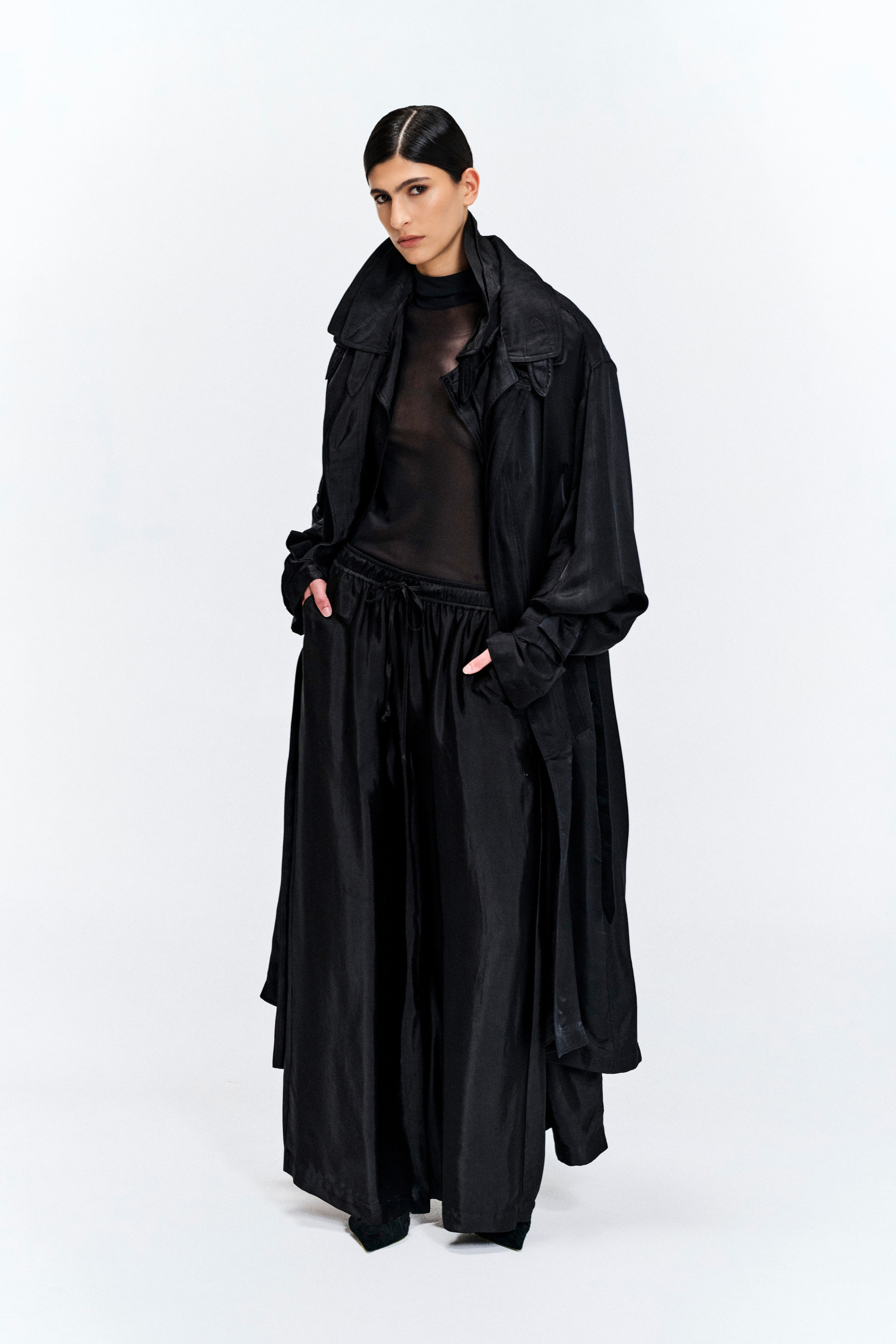 Model wearing a black silk longline coat with a double collar by KimC Studio.