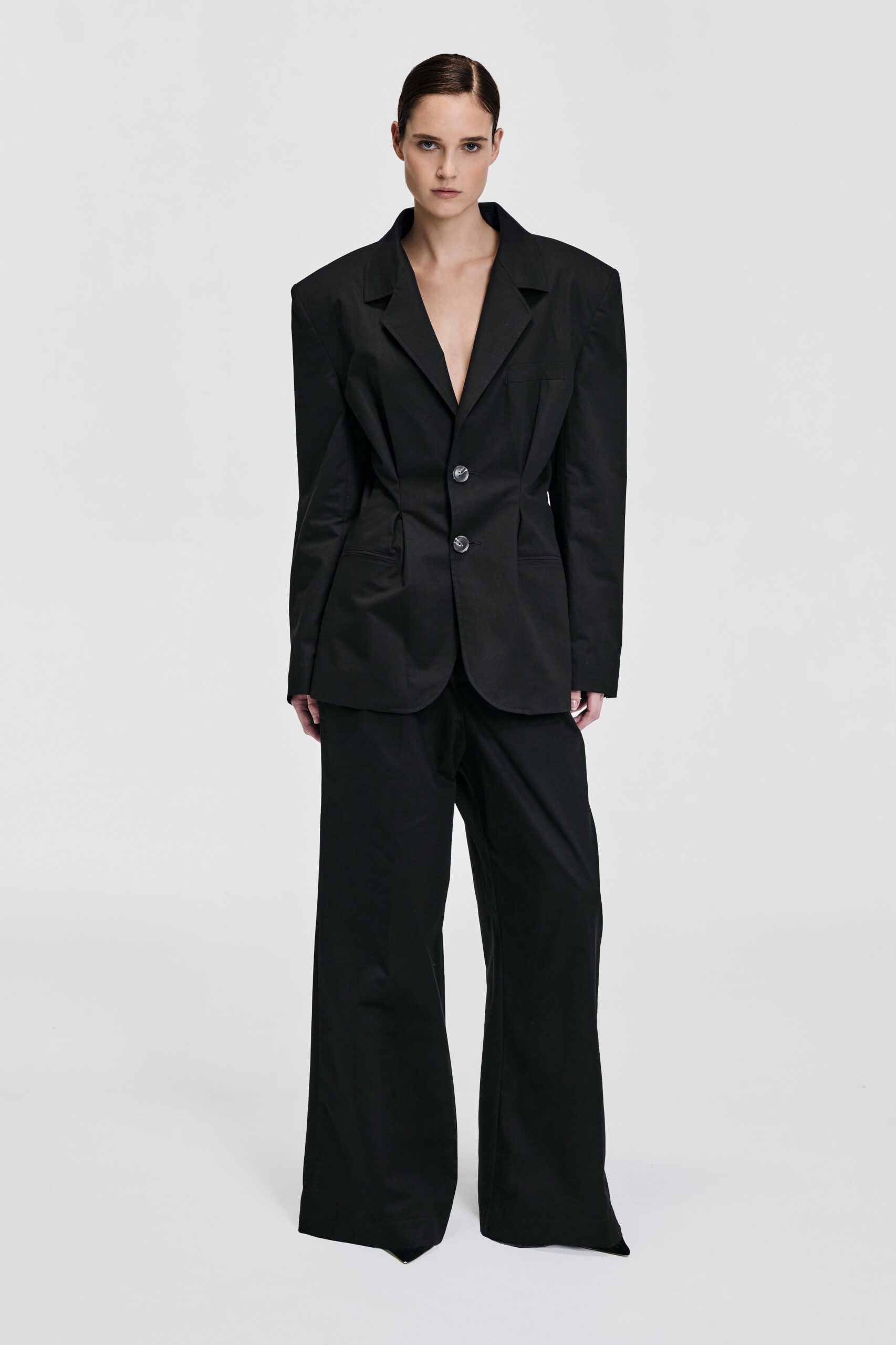 Front view of model wearing a black tailored blazer with structured shoulders and waist-defining shaping by KimC Studio.