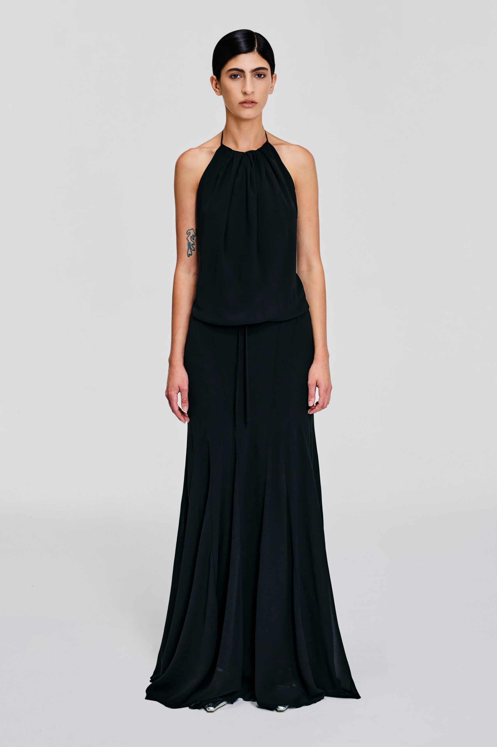 Model wearing a gathered halter maxi dress with relaxed blouson bodice, adjustable waist tie, satin lining and bias-cut floor-length skirt by KimC Studio.
