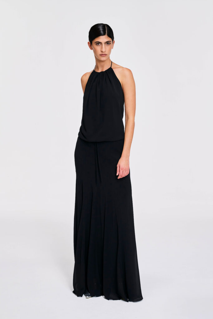 Model wearing a gathered halter maxi dress with relaxed blouson bodice, adjustable waist tie, satin lining and bias-cut floor-length skirt by KimC Studio.