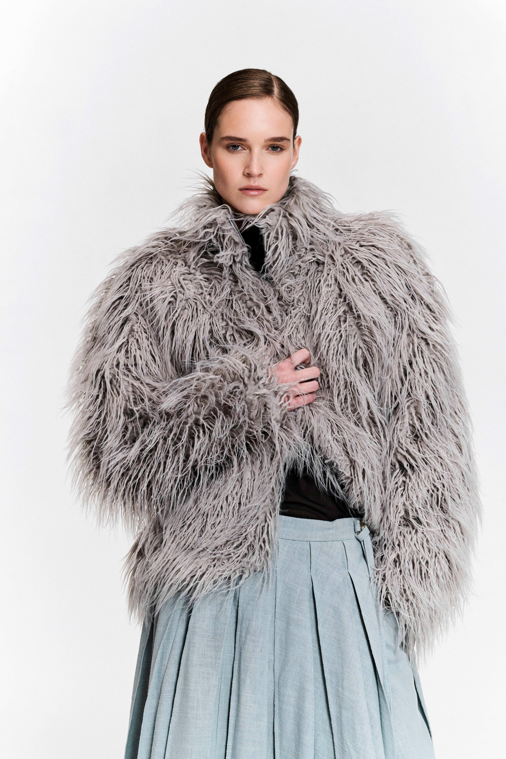 Front view of model wearing grey faux fur jacket with zip, drawstring hem by KimC Studio.
