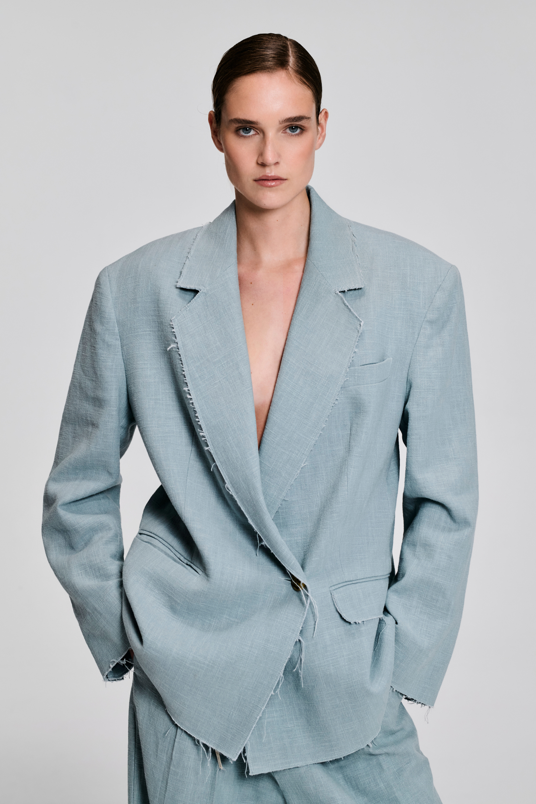 Detail of pale blue linen suit with oversized blazer and wide-leg trousers by KimC Studio.