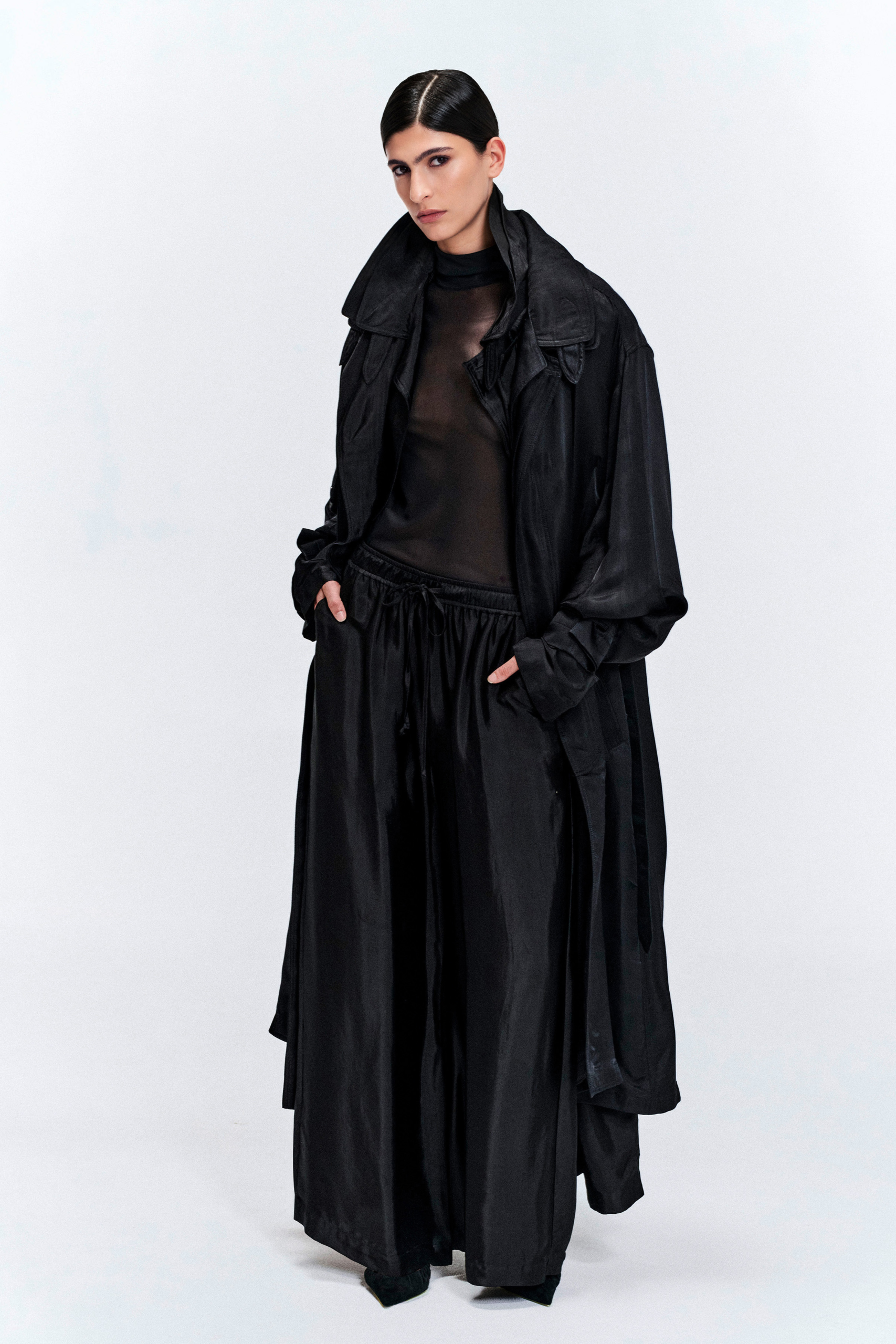 Model wearing a black silk longline coat with a double collar by KimC Studio.
