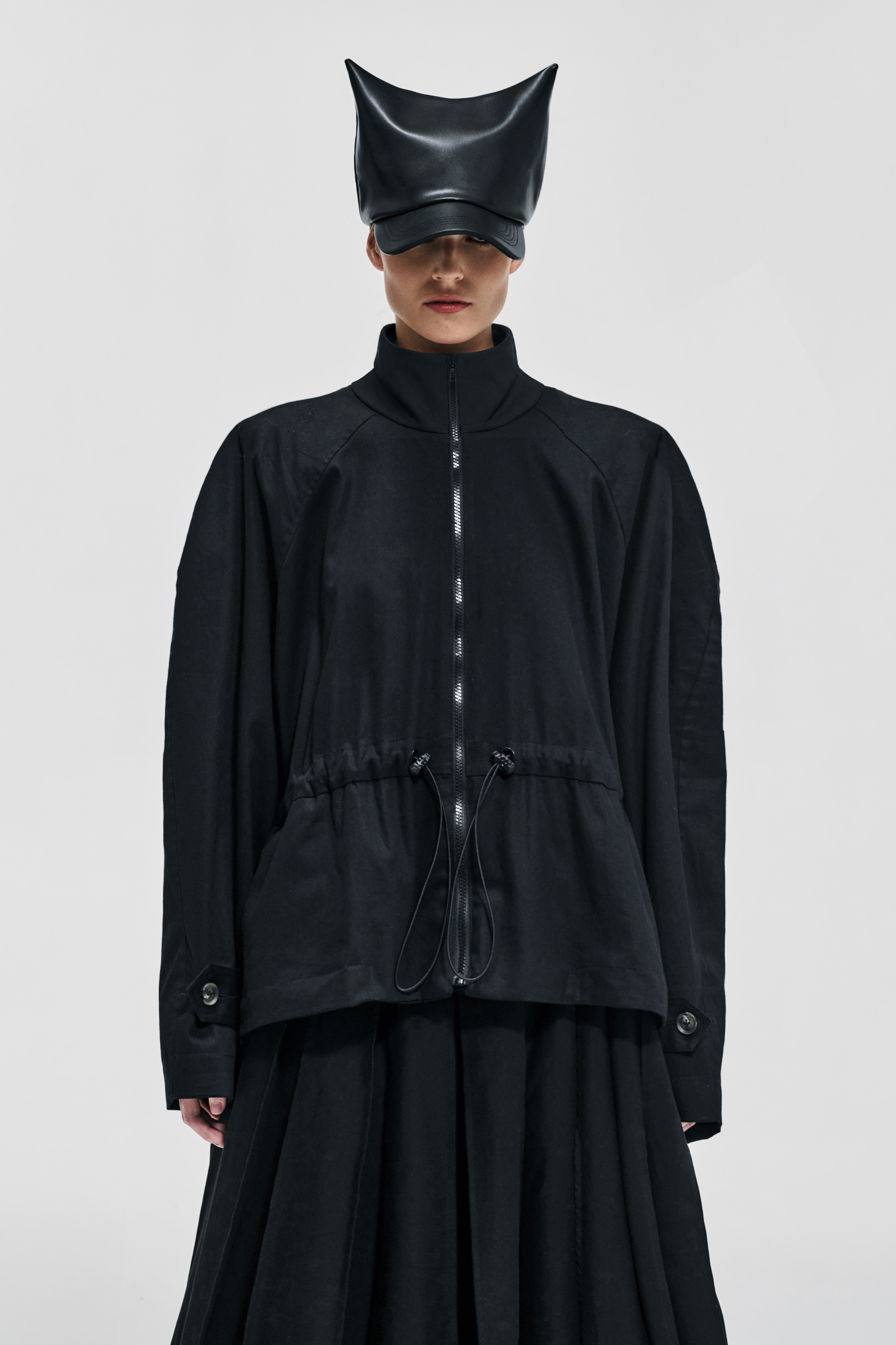 Front view of KIMC STUDIO black cotton drawcord jacket with high collar and zip fastening