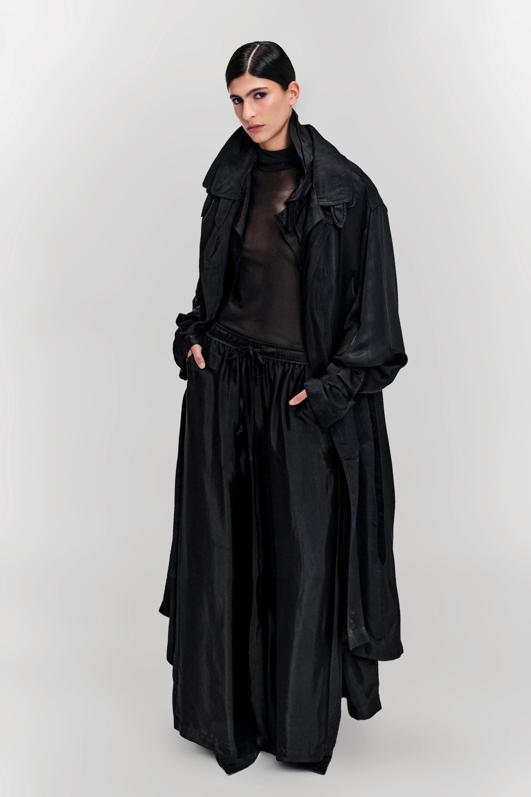 Model wearing a black silk longline coat with a double collar by KimC Studio.