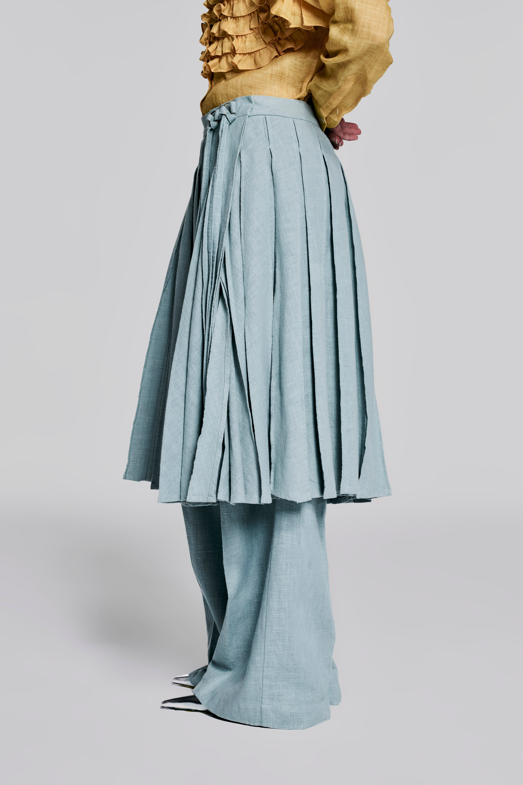 Side view of KIM C STUDIO pale blue linen pleated wrap skirt